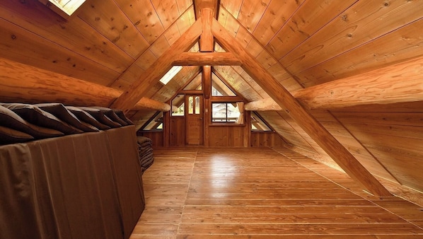 Une chambre mansardée en bois, avec un plafond en pente, un canapé et une fenêtre.