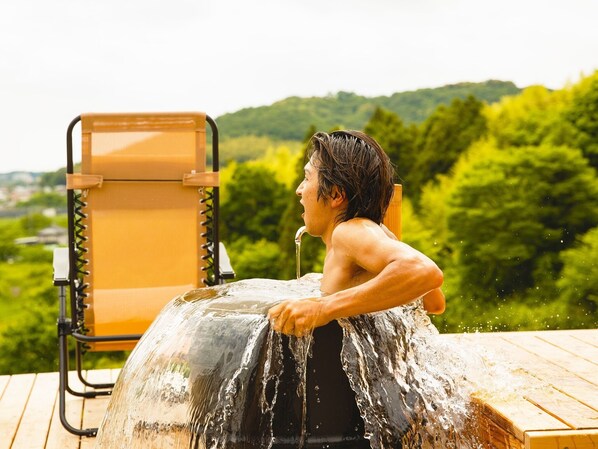 A person sitting in a hot tub with a view of a forested landscape.