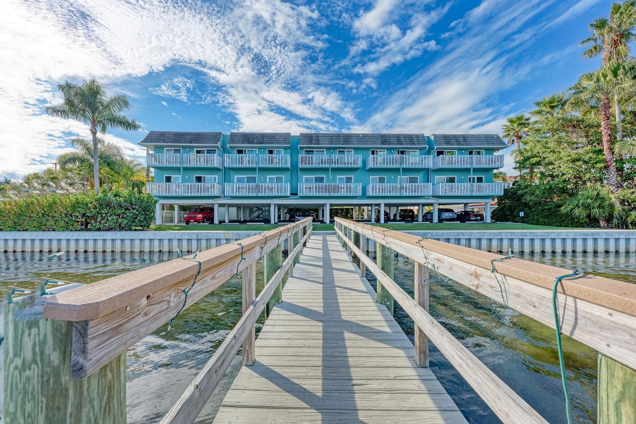 A waterfront hotel with a wooden boardwalk leading to a building with multiple balconies.