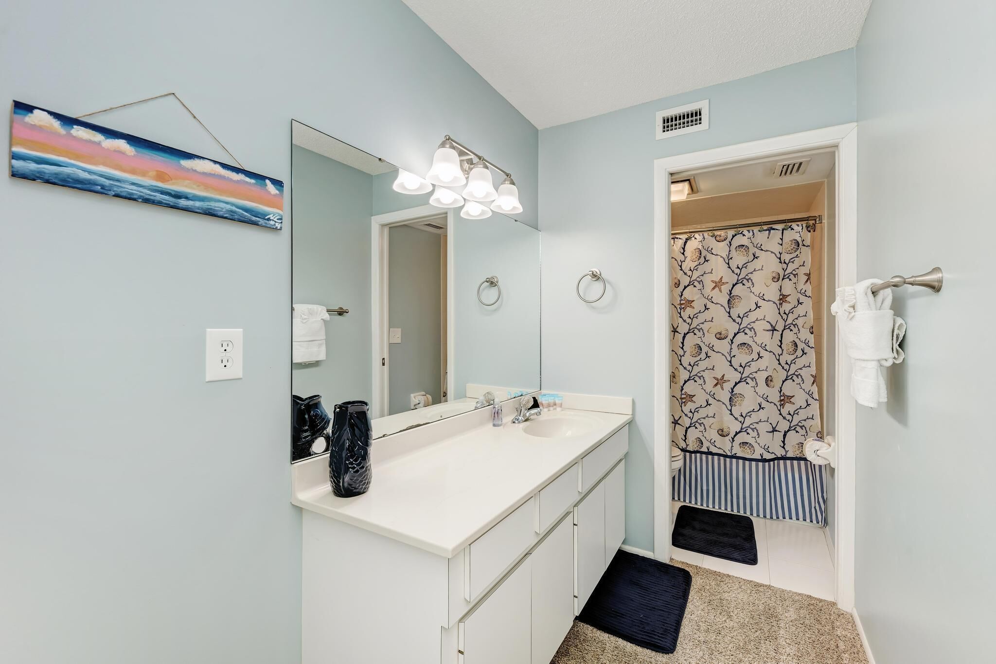 A bathroom with a white sink, a large mirror, and a shower curtain with a tree pattern.