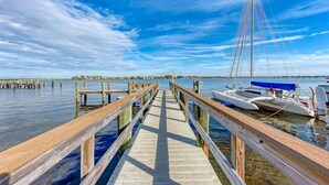 A wooden pier leading to a dock with boats moored at the end. - Anna Maria Island Beach Palms 8B (Bradenton Beach)