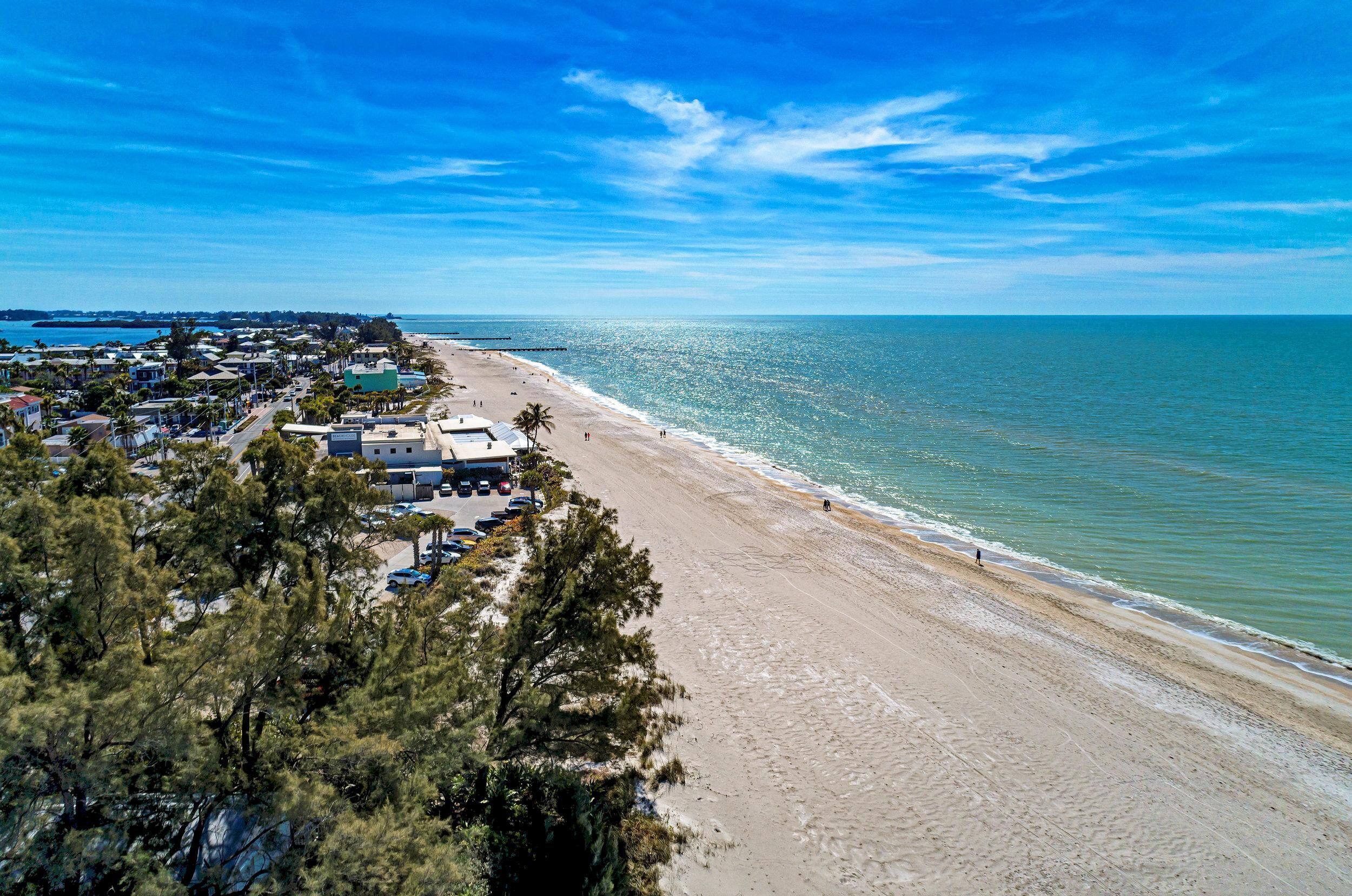 Uma área costeira com praia, fileira de casas e céu claro.