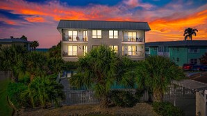 A two-story building with balconies, surrounded by palm trees and a swimming pool. - Anna Maria Island Beach Waves (Bradenton Beach)