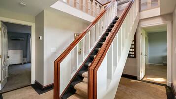 A staircase with wooden railings and beige carpeted steps leading to a second floor.