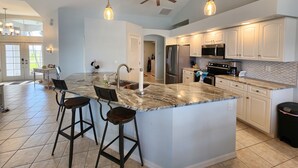 A spacious kitchen with a large island, modern appliances, and pendant lighting.