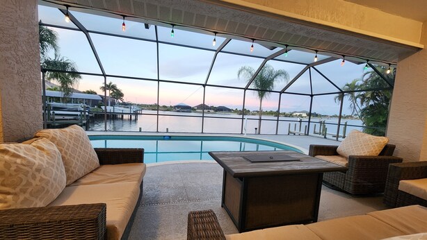 A poolside area with wicker furniture and a view of the water.