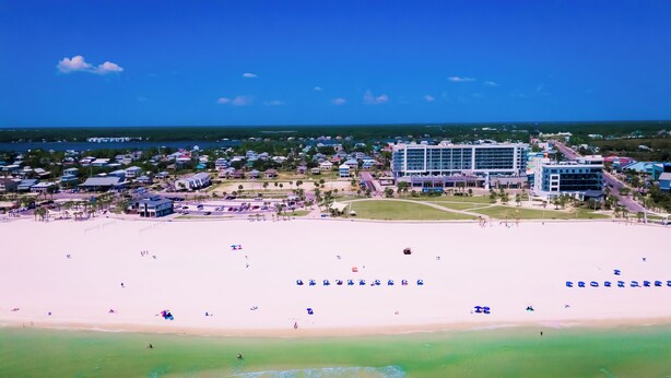 A coastal resort with a beachfront, a large hotel building, and a marina.