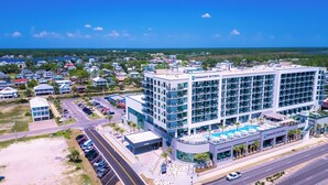 A modern hotel with a pool, multiple floors, and a view of the surrounding area.