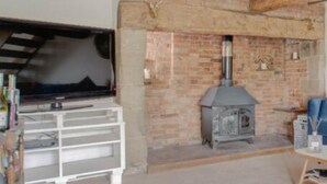 A room with exposed wooden beams, a brick fireplace, and a white entertainment unit. - Beautiful 3-bed House in the Hamlet of Ham Green (Redditch)