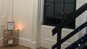 A room with a large window, a wooden floor, and a staircase.