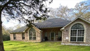 A two-story brick house with a sloped roof, large windows, and a front porch.