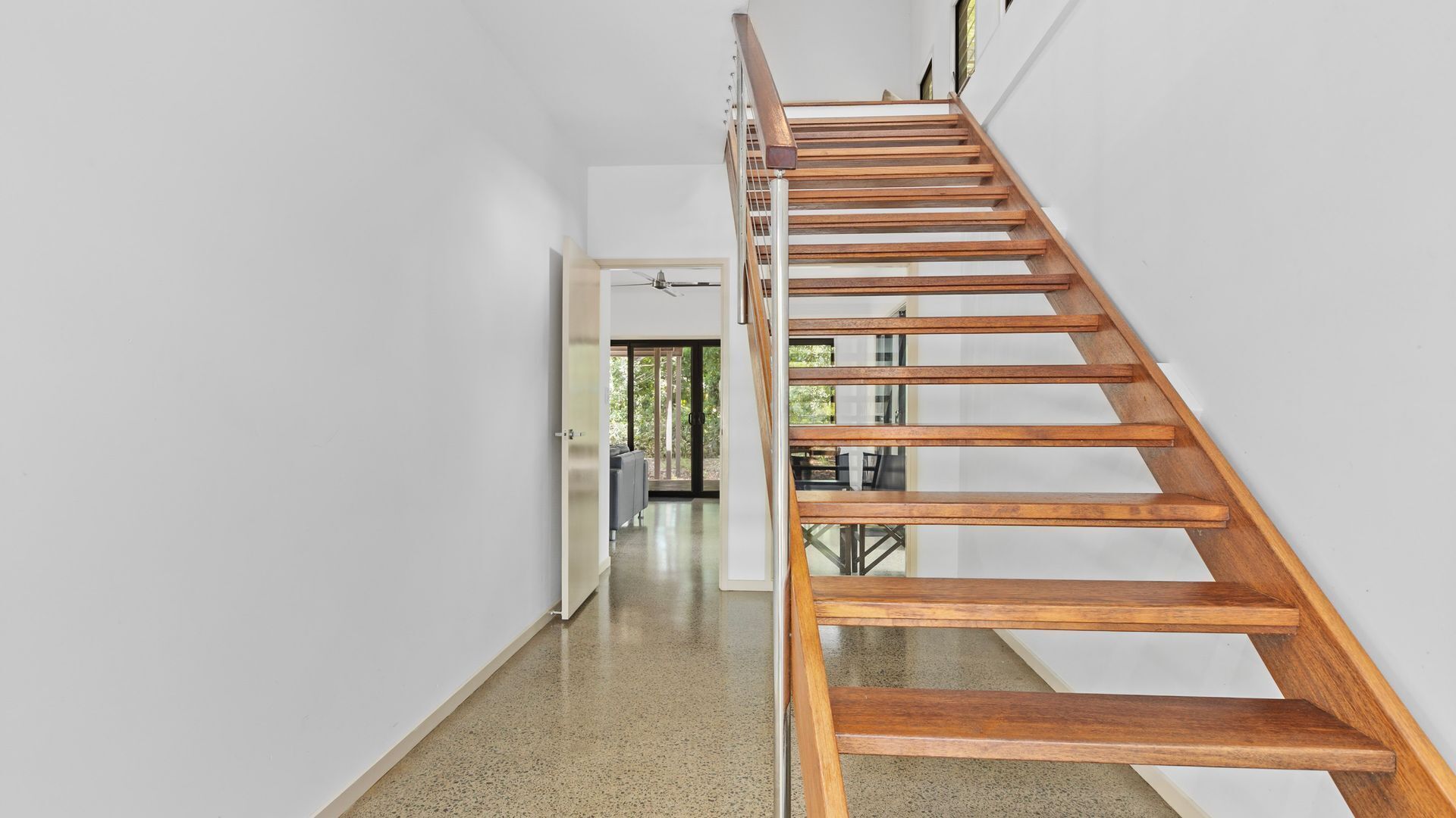 Un intérieur moderne avec un escalier en bois, un couloir et une porte donnant sur une pièce avec vue.
