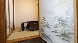 Experience serene tranquility in this traditional Japanese-style room, featuring a tatami floor, a low desk, and a beautiful landscape painting.