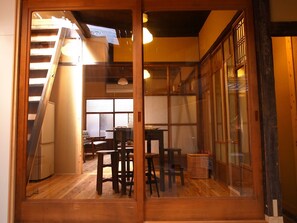 Ein traditioneller japanischer Raum mit Schiebetüren, einer Holztreppe und einem Essbereich mit Hocker und Tisch.