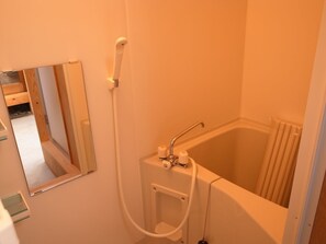 Ein kleines Badezimmer mit einer Badewanne, einer Dusche und einem Spiegel.