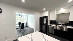 A modern kitchen with a white countertop, stainless steel appliances, and a black refrigerator.