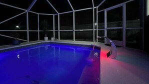 An indoor swimming pool with a glass enclosure, surrounded by windows.