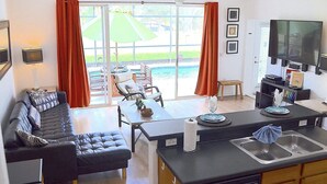 A modern living room with a sofa, a dining table, and a kitchen area with a TV and sink. - Perfect 5 bedroom family home with Pool & Jacuzzi near Disney World (Davenport)