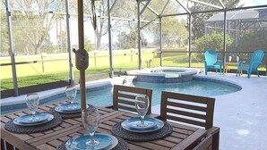 A covered outdoor area with a pool, dining table with chairs, and lounge chairs. - Perfect 5 bedroom family home with Pool & Jacuzzi near Disney World (Davenport)