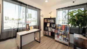 Une pièce comprenant un bureau, une bibliothèque et une grande fenêtre avec des rideaux.
