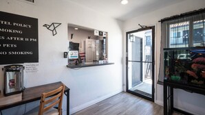 Un hall d’hôtel comprenant un comptoir d’accueil, une machine à café, une chaise en bois et un aquarium.