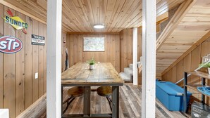 Een houten interieur met een centrale tafel, een kamerplant en een blauwe opbergunit.