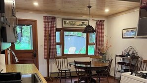 A kitchen with a wooden countertop, a dining table with chairs, a window with curtains, and a stove. - West Bay Hideaway on Big Moose Lake (Webb)