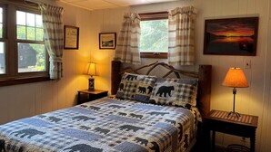 A bedroom with a bed, two bedside lamps, a framed picture, and a window with curtains. - West Bay Hideaway on Big Moose Lake (Webb)