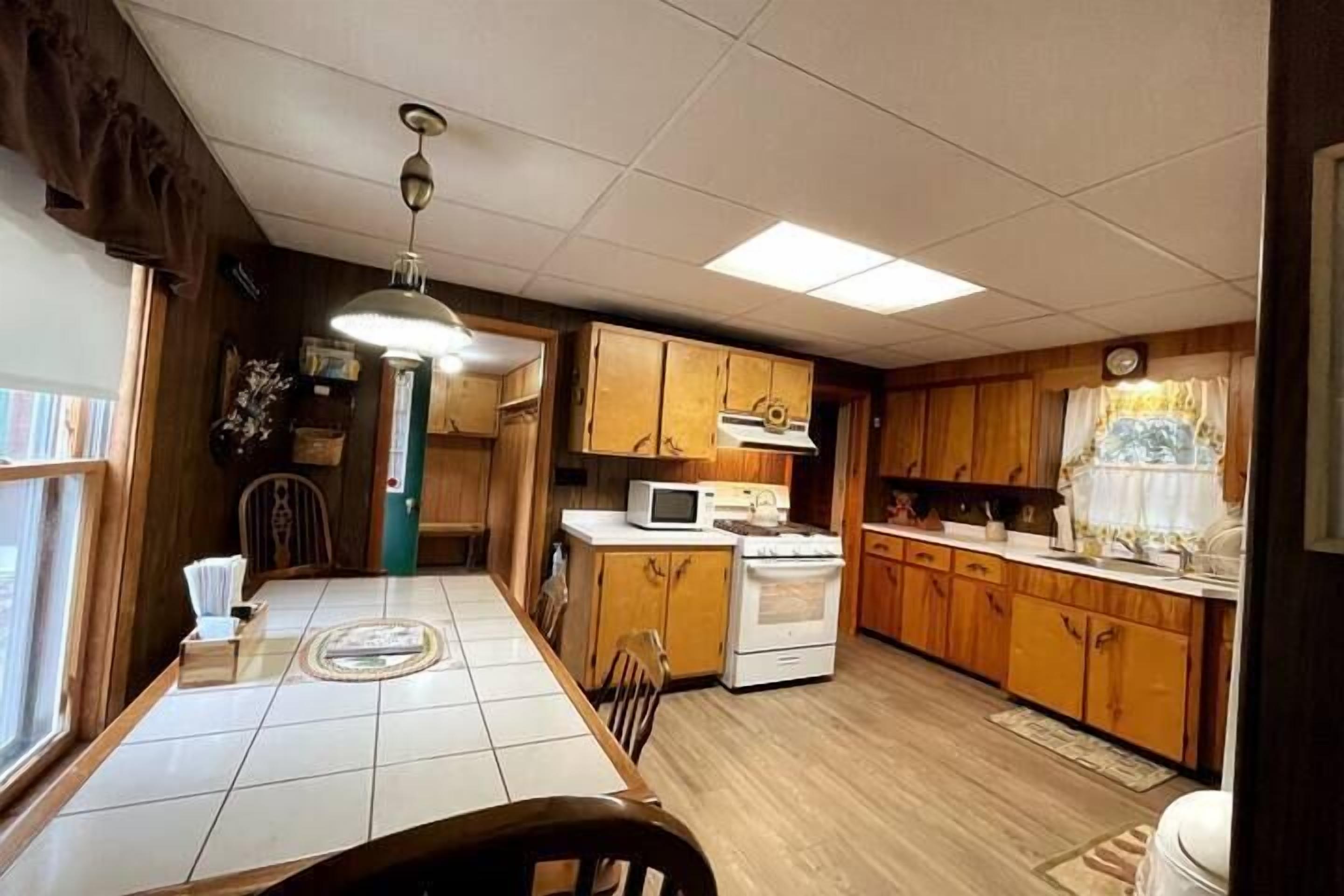 A kitchen with wooden cabinets, a microwave, and a stove.