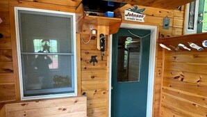 Een houten cabinestijl interieur met een blauwgroene deur, een raam en een bordje met 'Johnson Outboard Motors'.