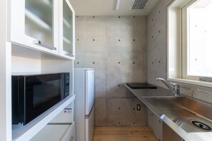 Compact kitchen with microwave oven, stainless steel sink, and window for natural light.