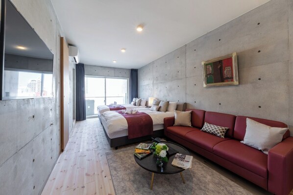 Relax in a stylish room with a large bed, a sofa, and a coffee table, offering a city view.