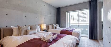A hotel room with two beds, a large window with curtains, and a concrete wall.