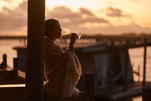 A person sitting by a waterfront, holding a glass. - Laguna Garzón LODGE (José Ignacio)