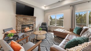 Un salon moderne avec une cheminée, un canapé en cuir et un téléviseur à écran plat fixé au-dessus de la cheminée.