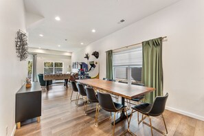 A spacious room with a long wooden table and black chairs, a foosball table, and a large window with curtains. - Lakefront Rooftop Hangout Hot Tub Fire Pit Arcades (Branson)