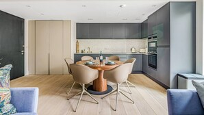 Une cuisine moderne dotée d’un îlot central, de meubles de couleur grise et d’un four encastré.