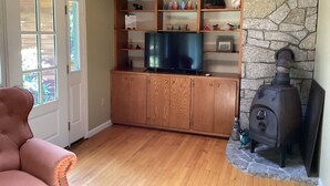 A living room with wooden cabinets, a television, a stone fireplace, and a door with glass panels.