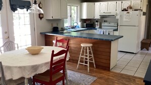 A kitchen with white cabinets, a wooden island, a dining table with chairs, and a refrigerator.