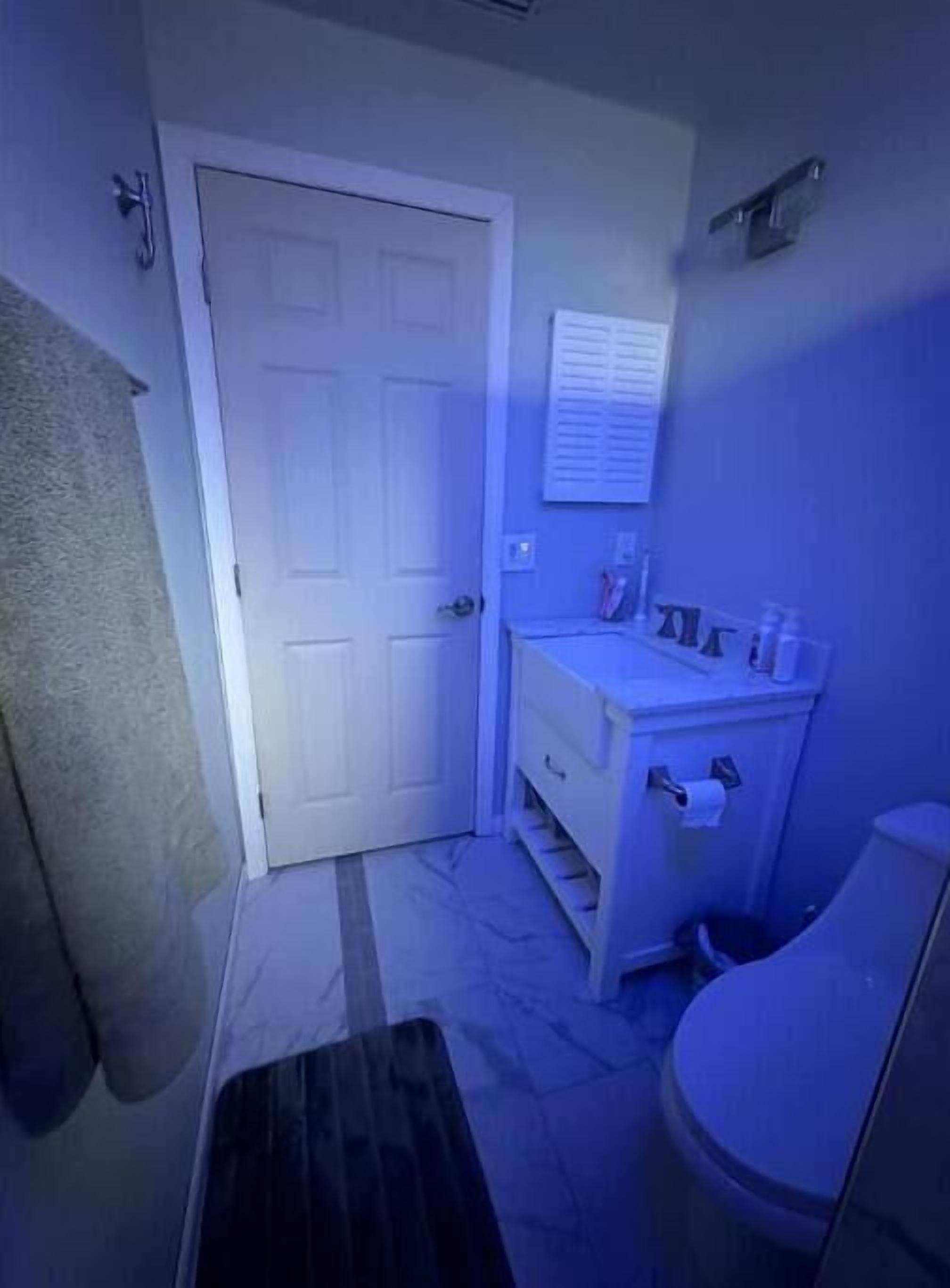 A bathroom with a white door, a sink, and a toilet.