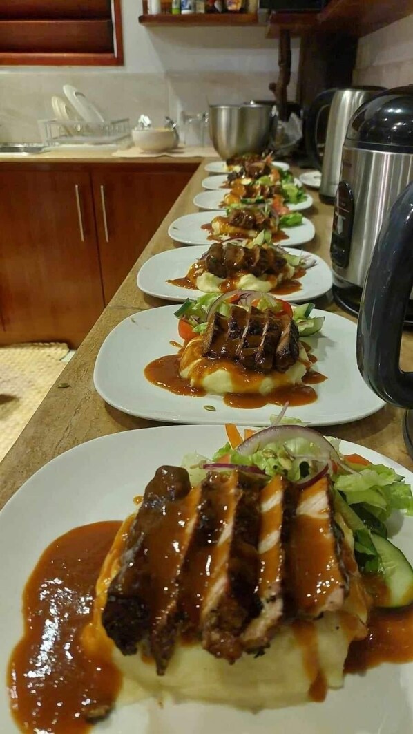A row of plates with food, a kettle, and a cabinet in the background.
