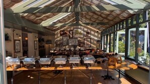 Une pièce spacieuse avec un plafond haut, de grandes fenêtres et une longue table dotée de plusieurs points de service.
