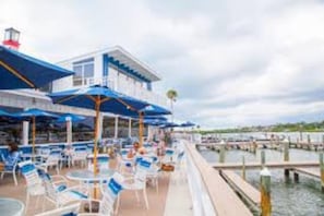 A waterfront restaurant with outdoor seating, a pool, and a building with a blue roof. - Heated Pool Close to St Pete Tampa Pet Friendly (Pinellas Park)