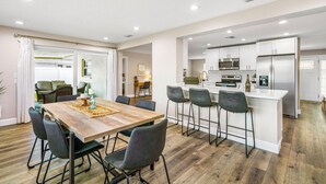 A modern kitchen with white cabinets, stainless steel appliances, and a central island with bar stools. - Heated Pool Hot tub Clearwater Dunedin Pet Friendly (Clearwater)