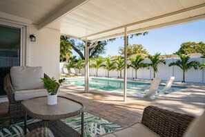 A covered outdoor area with a pool, lounge chairs, and a table with a plant. - Heated Pool Hot tub Clearwater Dunedin Pet Friendly (Clearwater)