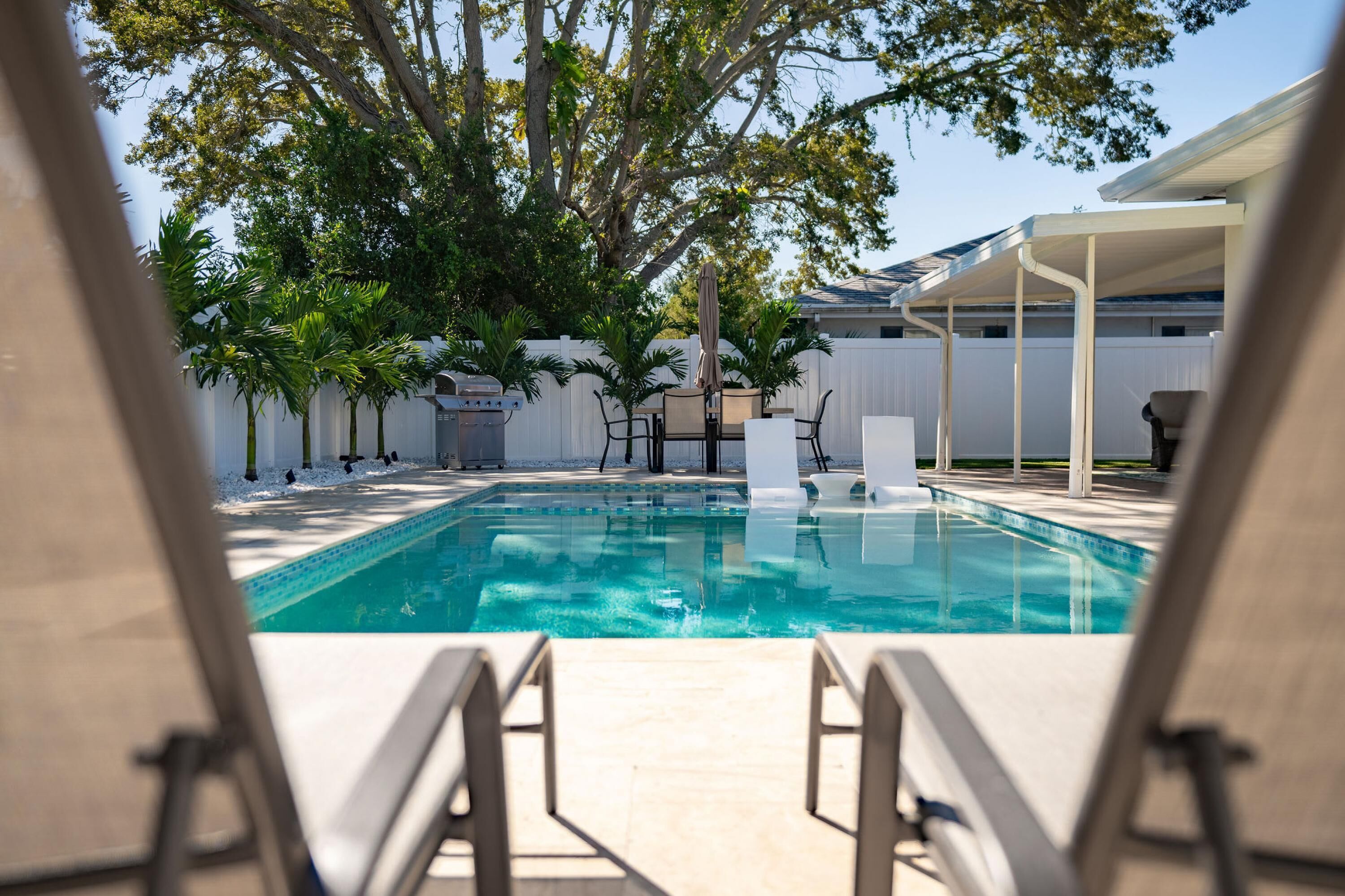 A pool area with lounge chairs and a barbecue grill.