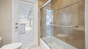 A modern bathroom with a glass-enclosed shower, a white toilet, and beige tiled walls. - Heated Pool Home Pool Table Spacious Family (Largo)