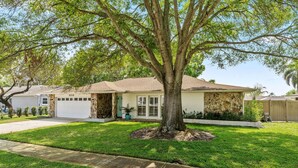 A single-story house with a stone facade, a large tree in the front yard, and a well-maintained lawn. - Heated Pool Home Pool Table Spacious Family (Largo)