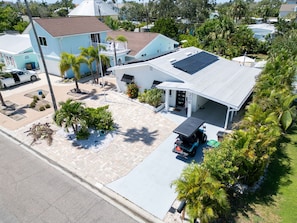 Une propriété résidentielle dotée d’un panneau solaire, d’un garage fermé et d’une allée permettant de garer un véhicule de type voiturette de golf.
