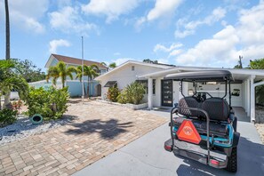 Une voiturette de golf est garée dans une allée, avec une maison en arrière-plan.